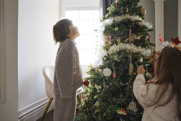 Junge mit Mädchen beim Schmücken des Weihnachtsbaums zu Hause - MDOF00391