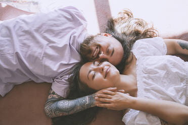 Glückliches romantisches Paar mit geschlossenen Augen auf dem Bett zu Hause liegend - NDEF00288