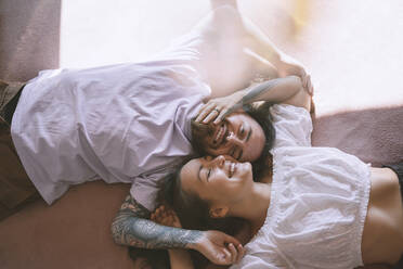 Glückliches romantisches Hipster-Paar, das zu Hause auf dem Bett liegt - NDEF00290