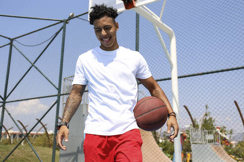 Happy young man with basketball at sports court - SYEF00027