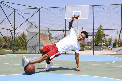 Mann übt Tanzschritte mit Basketball auf dem Sportplatz - SYEF00028