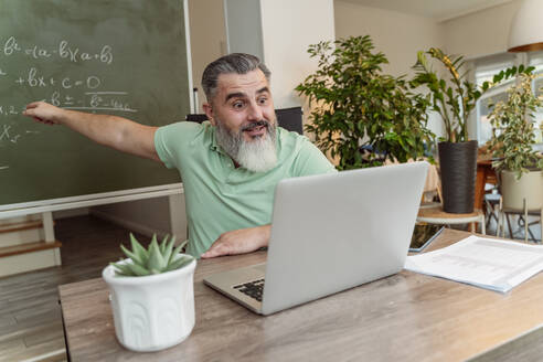 Lehrer, der eine Online-Vorlesung per Videoanruf am Laptop am Schreibtisch hält - OSF01218