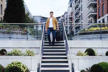 Young man with bag moving down steps - ASGF03169