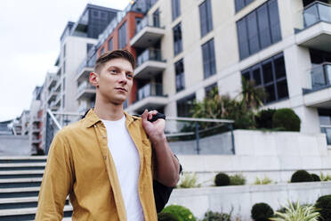 Thoughtful young handsome man carrying bag - ASGF03171