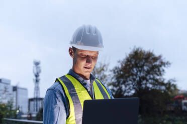 Engineer wearing hardhat using laptop - ASGF03182