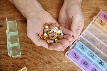 Man holding different pills in hand on table - EYAF02375