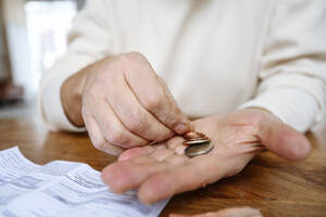 Man counting coins on hand at home - EYAF02383
