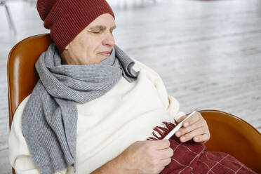 Älterer Mann in warmer Kleidung hält Thermometer - EYAF02393