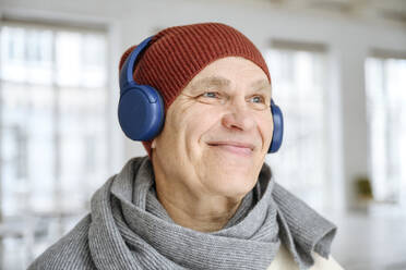 Nachdenklicher Mann, der zu Hause über Kopfhörer Musik hört - EYAF02396