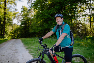 Ein aktiver älterer Mann, der im Sommer im Park Fahrrad fährt, Konzept des gesunden Lebensstils. - HPIF03508