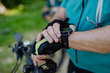 Nahaufnahme eines älteren Motorradfahrers, der auf seine Sport-Smartwatch schaut, um seine Leistung zu überprüfen. - HPIF03523