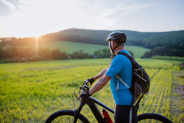 Ein aktiver älterer Mann, der im Sommer im Park Fahrrad fährt, Konzept des gesunden Lebensstils. - HPIF03582