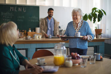 Lächelnde ältere Frauen beim Frühstück in einem Pflegeheim. - HPIF03600