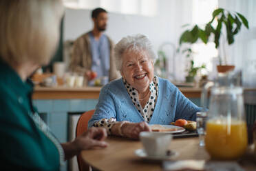 Eine lächelnde ältere Frau genießt das Frühstück in einem Pflegeheim. - HPIF03601