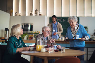 Eine Gruppe fröhlicher Senioren genießt das Frühstück in einem Pflegeheim. - HPIF03604