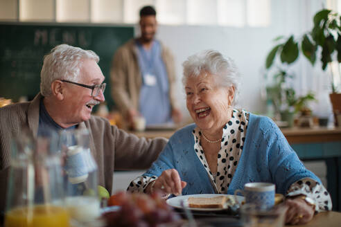 Eine lächelnde ältere Frau und ein Mann genießen das Frühstück in einem Pflegeheim. - HPIF03607