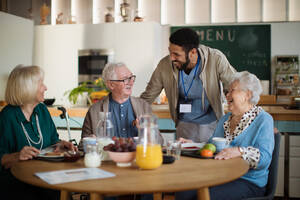 Eine Gruppe fröhlicher Senioren genießt das Frühstück in einem Pflegeheim. - HPIF03612