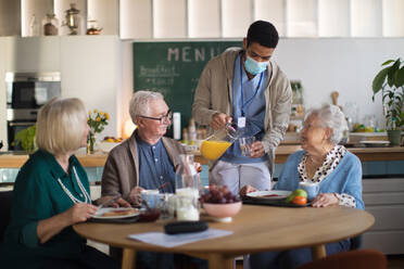 Eine Gruppe fröhlicher Senioren genießt das Frühstück in einem Pflegeheim. - HPIF03613