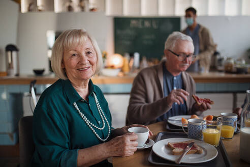 Eine lächelnde ältere Frau und ein Mann genießen das Frühstück in einem Pflegeheim. - HPIF03619
