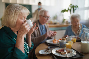 Eine Gruppe fröhlicher Senioren genießt das Frühstück in einem Pflegeheim. - HPIF03620
