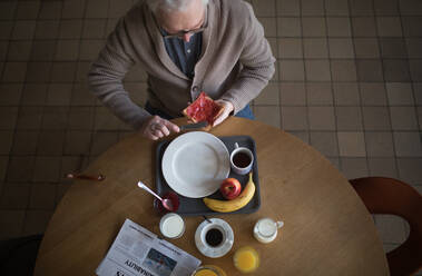 Draufsicht auf einen älteren Mann, der in einem Pflegeheim frühstückt. - HPIF03633