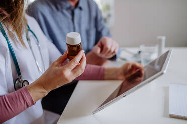 Eine medizinische Fachkraft oder eine Pflegekraft besucht einen älteren Mann zu Hause und erklärt ihm die Medikamentendosierung. - HPIF03656