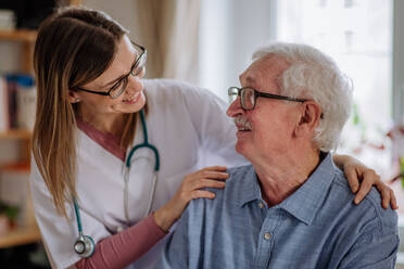 A healthcare worker or caregiver visiting senior man indoors at home. - HPIF03666