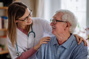 Eine Pflegekraft oder ein Pfleger besucht einen älteren Mann zu Hause. - HPIF03666