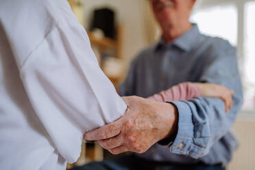 A close-up of doctor holding hand of senior patient and consoling him during medical visit at home. - HPIF03667