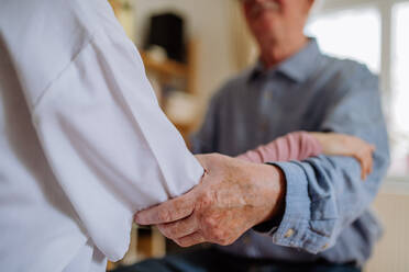 Nahaufnahme eines Arztes, der die Hand eines älteren Patienten hält und ihn bei einem Arztbesuch zu Hause tröstet. - HPIF03667