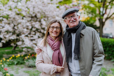 Eine erwachsene Tochter umarmt ihren älteren Vater draußen im Park an einem Frühlingstag. - HPIF03687