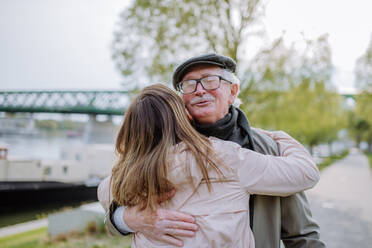 A rear view of adult daughter hugging her senior father when meeting him outdoors in street. - HPIF03692