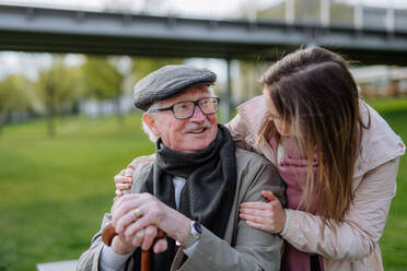 Ein glücklicher Senior mit seiner erwachsenen Tochter sitzt im Park. - HPIF03693