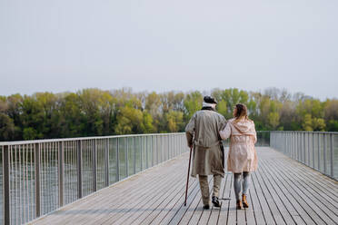 Rückansicht eines älteren Mannes mit Tochter bei einem Spaziergang auf dem Pier am Fluss. - HPIF03694