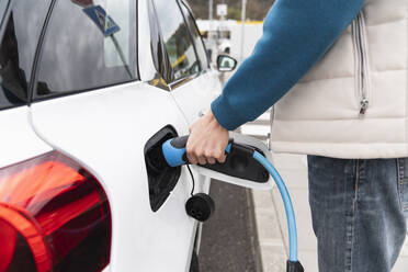 Man plugging charger in electric car - EKGF00215