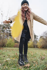 Playful girl wearing knit hat enjoying in park - MDOF00405