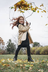 Fröhliches Mädchen hat Spaß mit Regenschirm im Park - MDOF00408