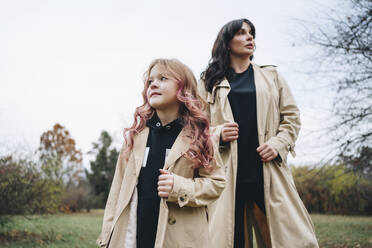 Girl and mother wearing trench coat at park - MDOF00411