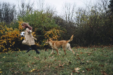 Fröhliches Mädchen spielt mit Hund im Park - MDOF00415