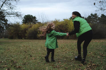 Happy mother with daughter holding hands and enjoying at park - MDOF00426