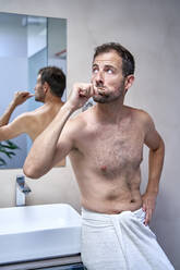 Mann beim Zähneputzen, der sich zu Hause an ein Waschbecken lehnt - VEGF06087