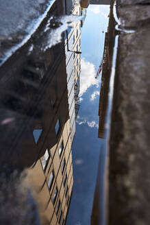 Spiegelung eines Gebäudes in einer Pfütze auf der Straße - VEGF06111