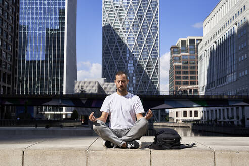 Man practicing meditation in front of building - VEGF06118