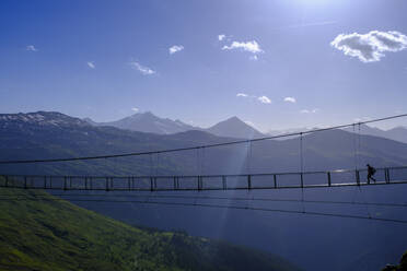 Österreich, Salzburg, Bad Gastein, Silhouette einer Person, die eine Hängebrücke über das Gasteinertal überquert - LBF03697
