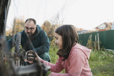 Father and daughter repairing bicycle together in back yard - OSF01235