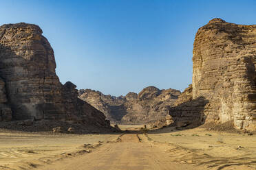Saudi Arabia, Medina Province, Al Ula, Desert road stretching between sandstone rock formations - RUNF04803