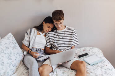 Mädchen studiert mit Bruder am Laptop im Schlafzimmer zu Hause - EGHF00687