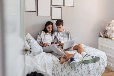 Geschwister lernen am Tablet-PC im Schlafzimmer zu Hause - EGHF00688