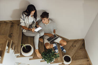 Sibling studying together through tablet PC sitting on staircase at home - EGHF00689