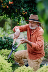 Ein älterer Mann schneidet Sträucher in seinem Garten. - HPIF03707